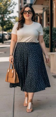 Woman in a white t-shirt and a dark pleated skirt walking outdoors