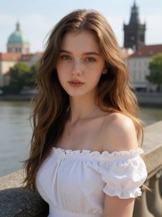 Woman with long hair wearing an off-shoulder top outdoors with a cityscape background