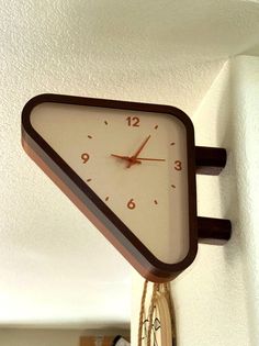 Triangle-shaped wall clock with a brown frame and white background
