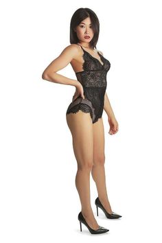 Woman in black lace lingerie and high heels posing against a white background