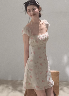 Woman in a floral dress with sunglasses on her head, looking to the side