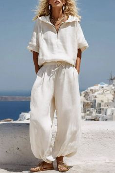 Woman in a white linen outfit with a cityscape and ocean in the background