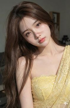 Woman with long brown hair wearing a yellow lace dress with exposed shoulders