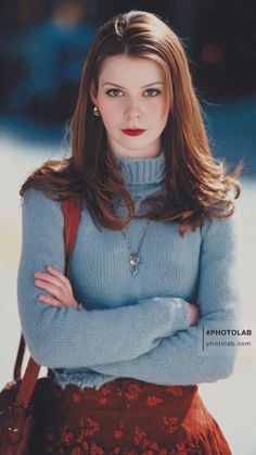 Woman with long hair wearing a blue turtleneck sweater and red lipstick