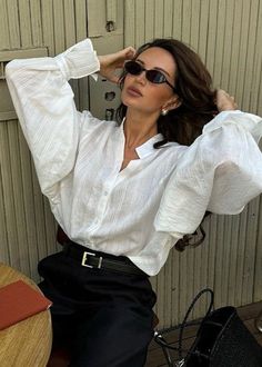 Woman with long hair wearing a white shirt and sunglasses indoors