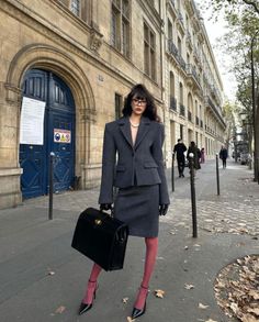 Woman in a grey skirt suit and pink tights on a city street