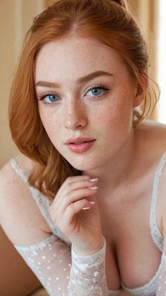 Woman with red hair and blue eyes wearing a lace top with cleavage