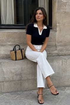 Woman in a black polo shirt and white pants sitting outdoors
