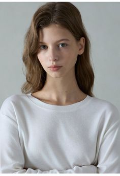 Woman with long brown hair wearing a white long-sleeved shirt