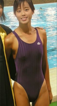 Young woman in a purple swimsuit smiling by a swimming pool