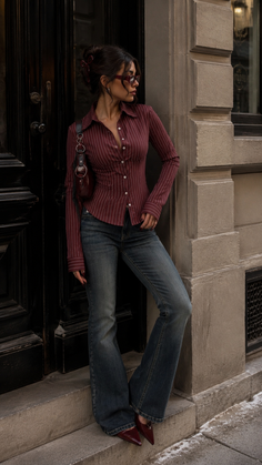 Woman in a pinstripe shirt and flared jeans posing outdoors