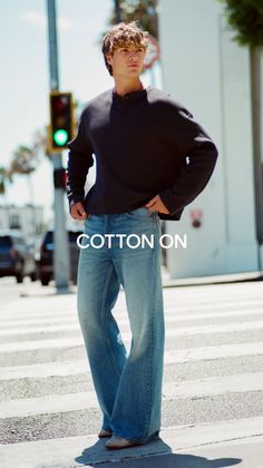 Man in a long sleeve shirt and wide leg jeans standing on a street