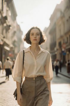 Woman with short hair in a white shirt and plaid pants on a sunlit street