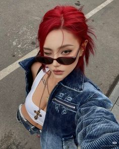 Woman with red hair and sunglasses wearing a denim jacket and white tank top