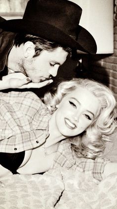 Man in a cowboy hat kissing a woman with blonde curly hair in a plaid shirt