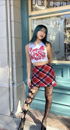 Woman with blue hair in a plaid skirt and crop top with heart pattern tights