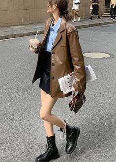 Woman in a brown leather jacket and black mini skirt walking on a street