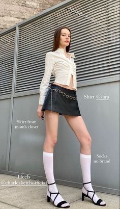 Woman in a white shirt, black mini skirt, and knee-high socks posing outdoors