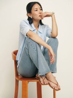 Woman in a blue striped shirt and jeans sitting on a wooden chair