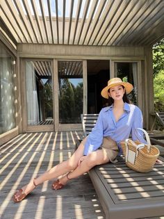 Woman in a straw hat and striped shirt sitting on a lounge chair outdoors