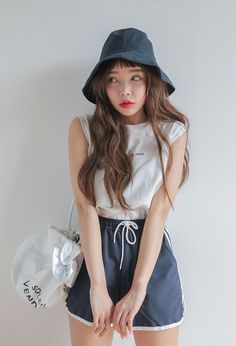 Woman in a bucket hat and athletic shorts against a white background