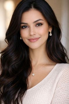 Woman with long dark hair wearing a light sweater and jewelry