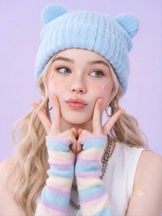 Blonde woman in a blue beanie and pastel fingerless gloves making a cute face
