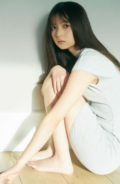 Woman with long hair sitting on a wooden floor in soft natural light