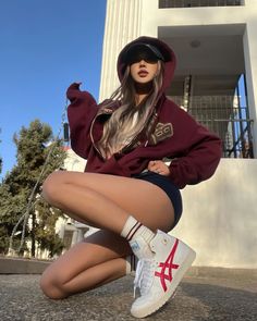 Woman in a hoodie and short shorts squatting outdoors
