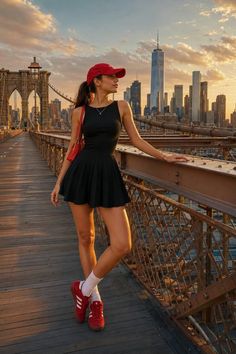 Woman in a black dress and red cap on the Brooklyn Bridge at sunset