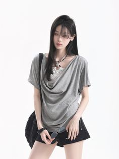 Woman with long black hair wearing a gray t-shirt and black shorts
