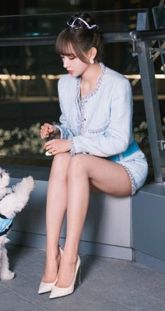 Woman in a light blue suit and high heels sitting outdoors at night