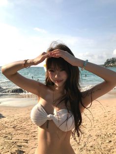 Woman in a white bikini top posing on a sunny beach
