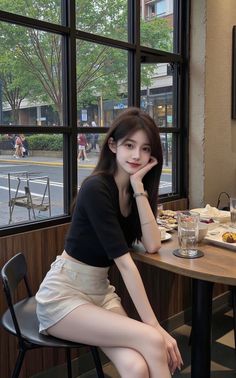 Woman with long dark hair in a black crop top and shorts sitting in a cafe