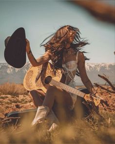 Woman in lingerie with a cowboy hat and guitar in a desert landscape