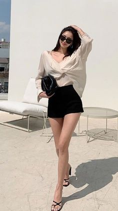 Woman in a white blouse and black shorts posing outdoors