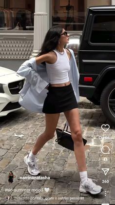 Woman in a white tank top and black mini skirt walking on a cobblestone street