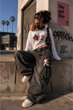 Woman in baggy jeans and an off-shoulder top posing on an urban street