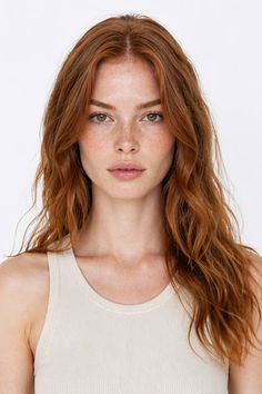 Woman with red hair and freckles wearing a tank top, looking directly at the camera