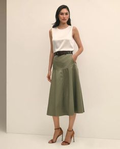 Woman in a white sleeveless top and olive midi skirt with high heels
