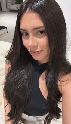 Woman with long black hair wearing a black top indoors