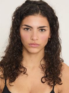 Woman with long curly dark hair and brown eyes looking directly at the camera