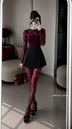 Woman in a burgundy lace top and red lace tights taking a mirror selfie