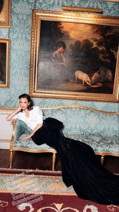 Woman in a long black dress and white shirt posing on an ornate sofa