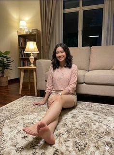 Woman with short hair sitting on a patterned rug in an indoor setting