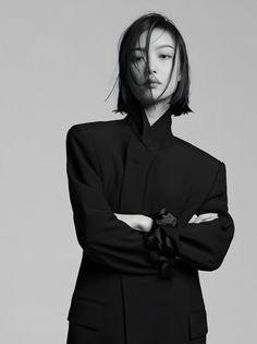 Woman with short hair and a black jacket posing with arms crossed in a studio