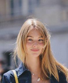 Young woman with blonde hair and freckles wearing a denim jacket and necklace