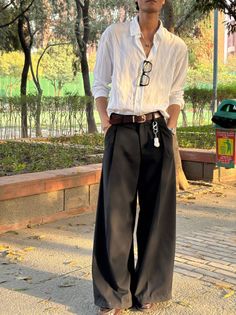 Person in a white shirt and wide leg pants standing outdoors