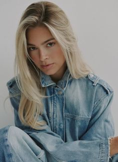 Woman with long blonde hair wearing a denim jacket, looking at the camera