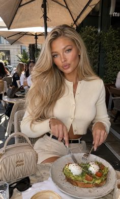 Woman with blonde hair eating avocado toast at an outdoor cafe